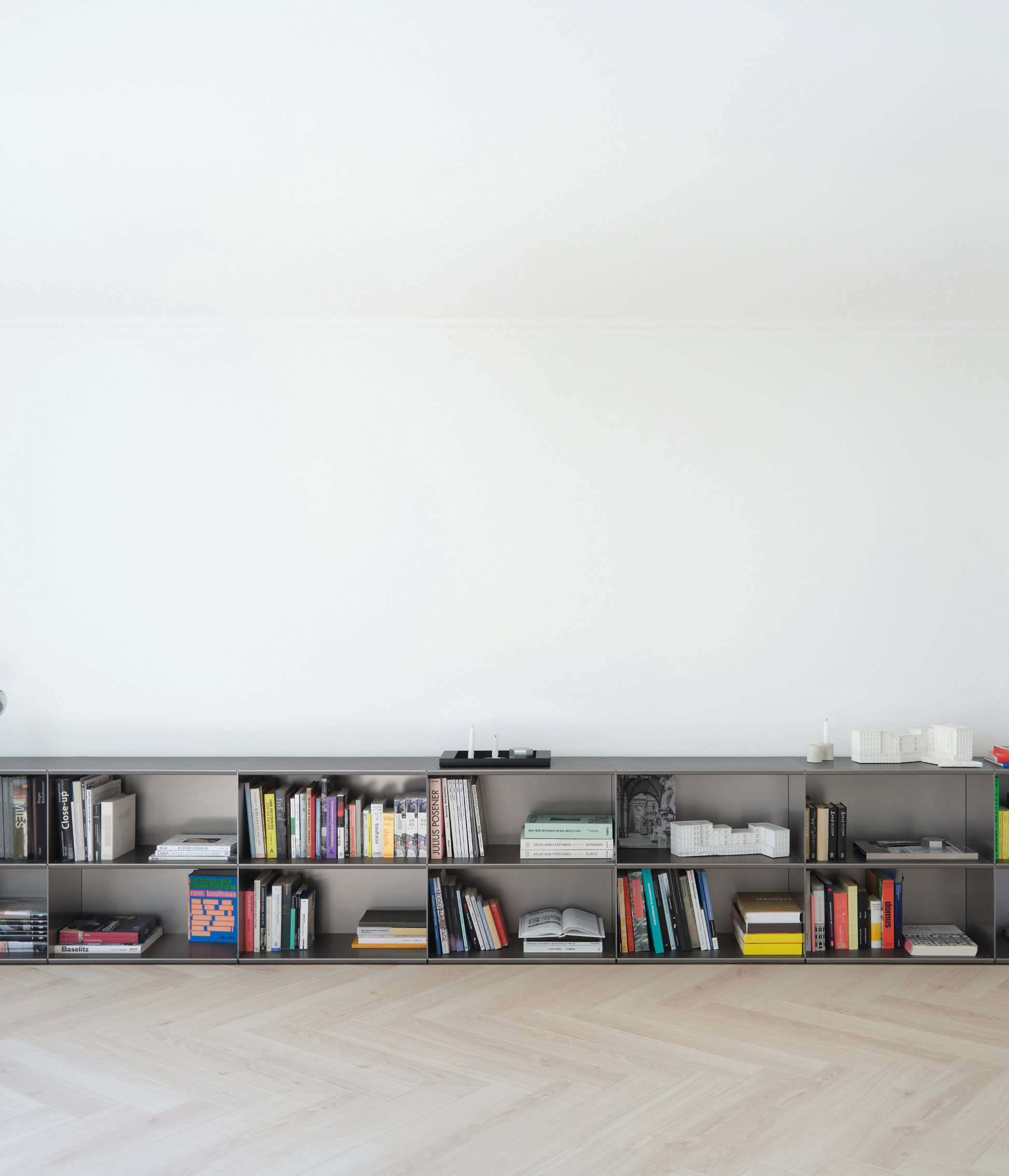 Modern modular M85 aluminum shelf in gunmetal with books and decor against a white wall