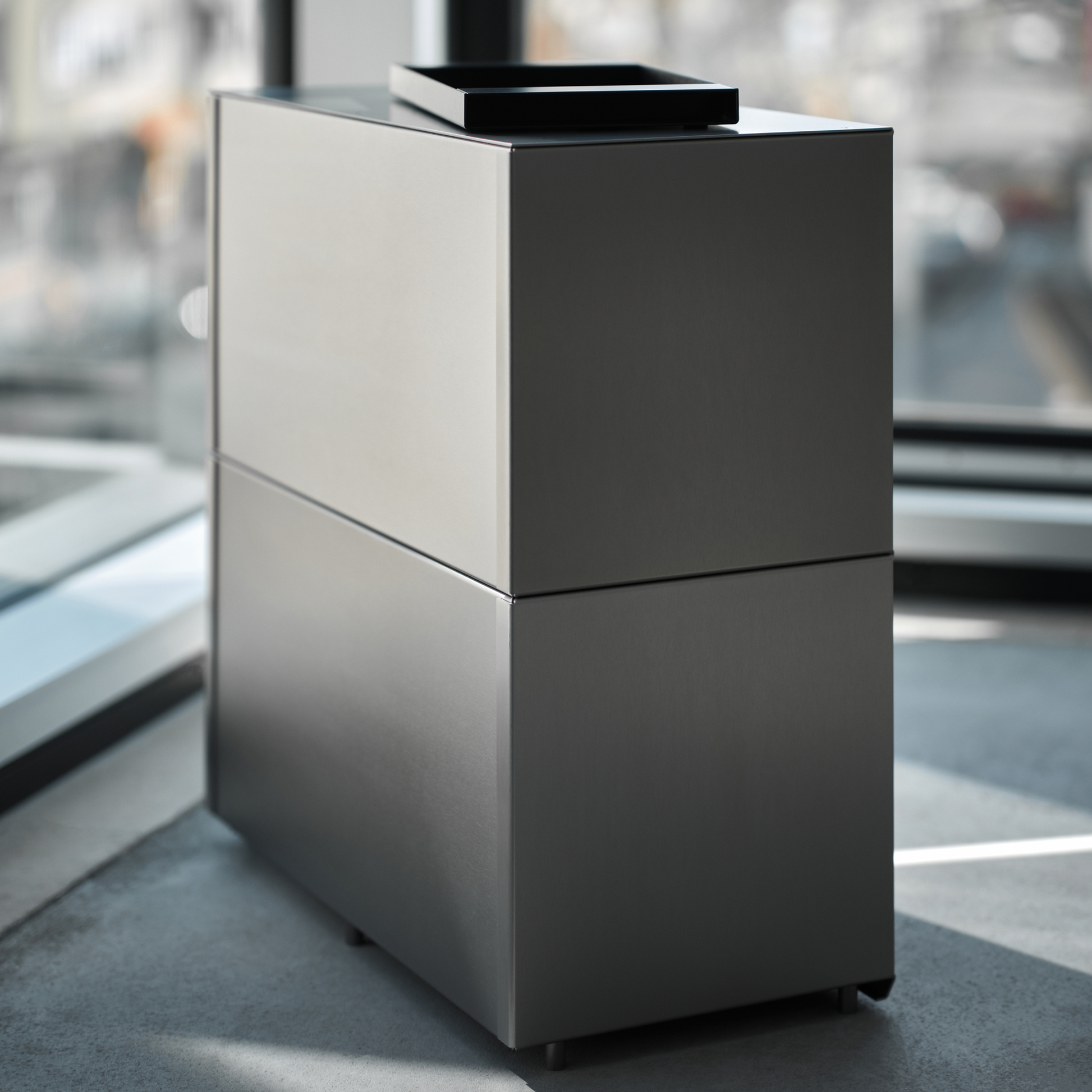 M85 modular aluminum shelf seen from the back with M85 black tray on top and big windows on the background