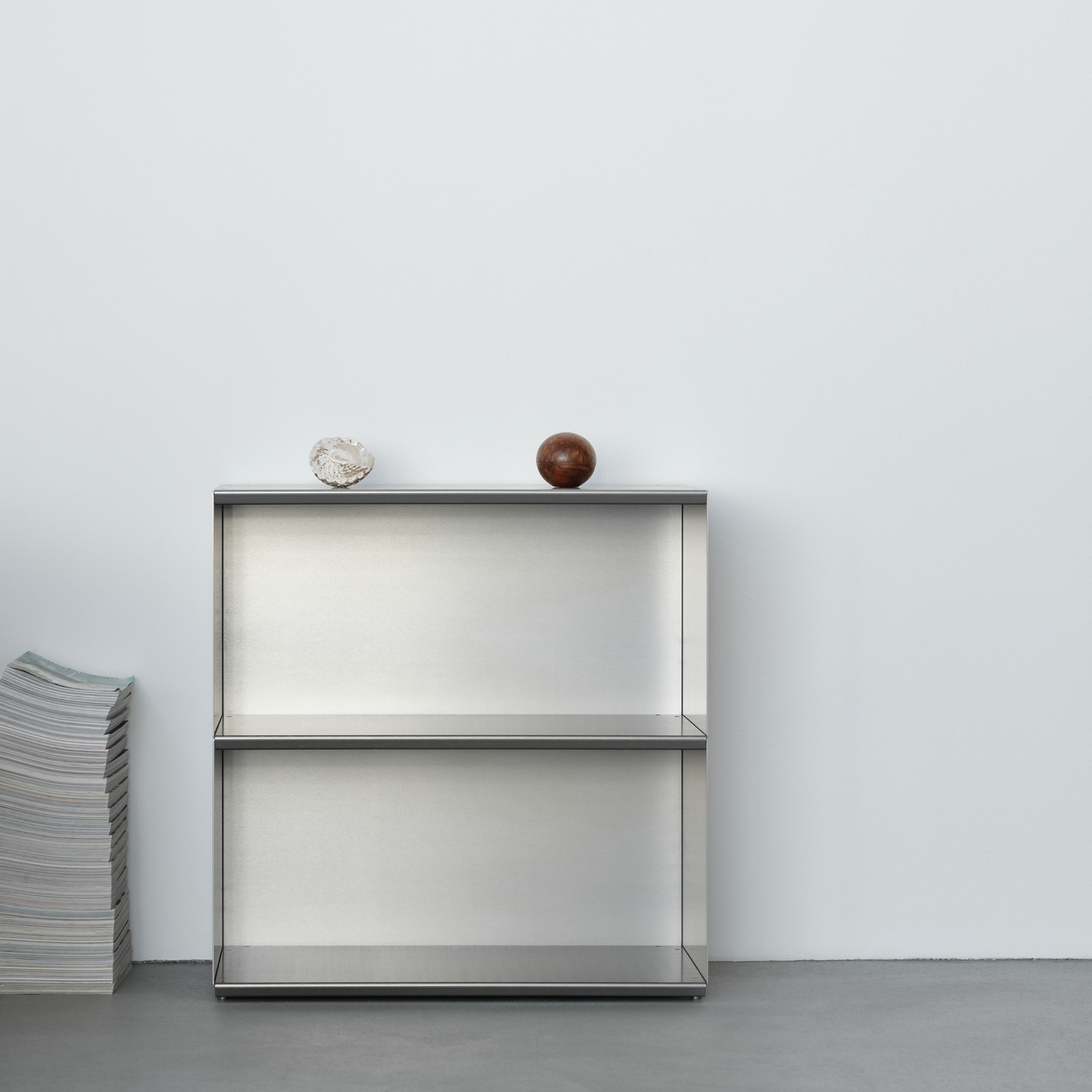 M85 aluminum bookshelf with two decorative items against a white wall