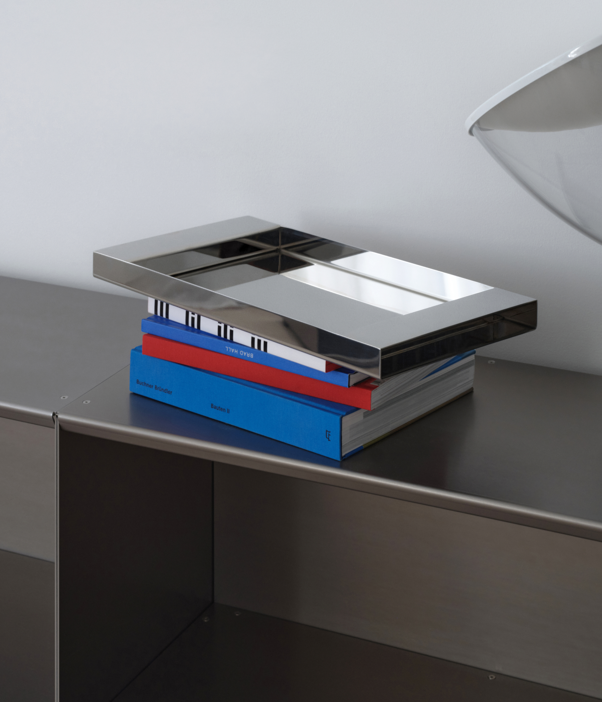 M85 stainless steel tray with mirror polish standing on M85 bookshelf on a book pile