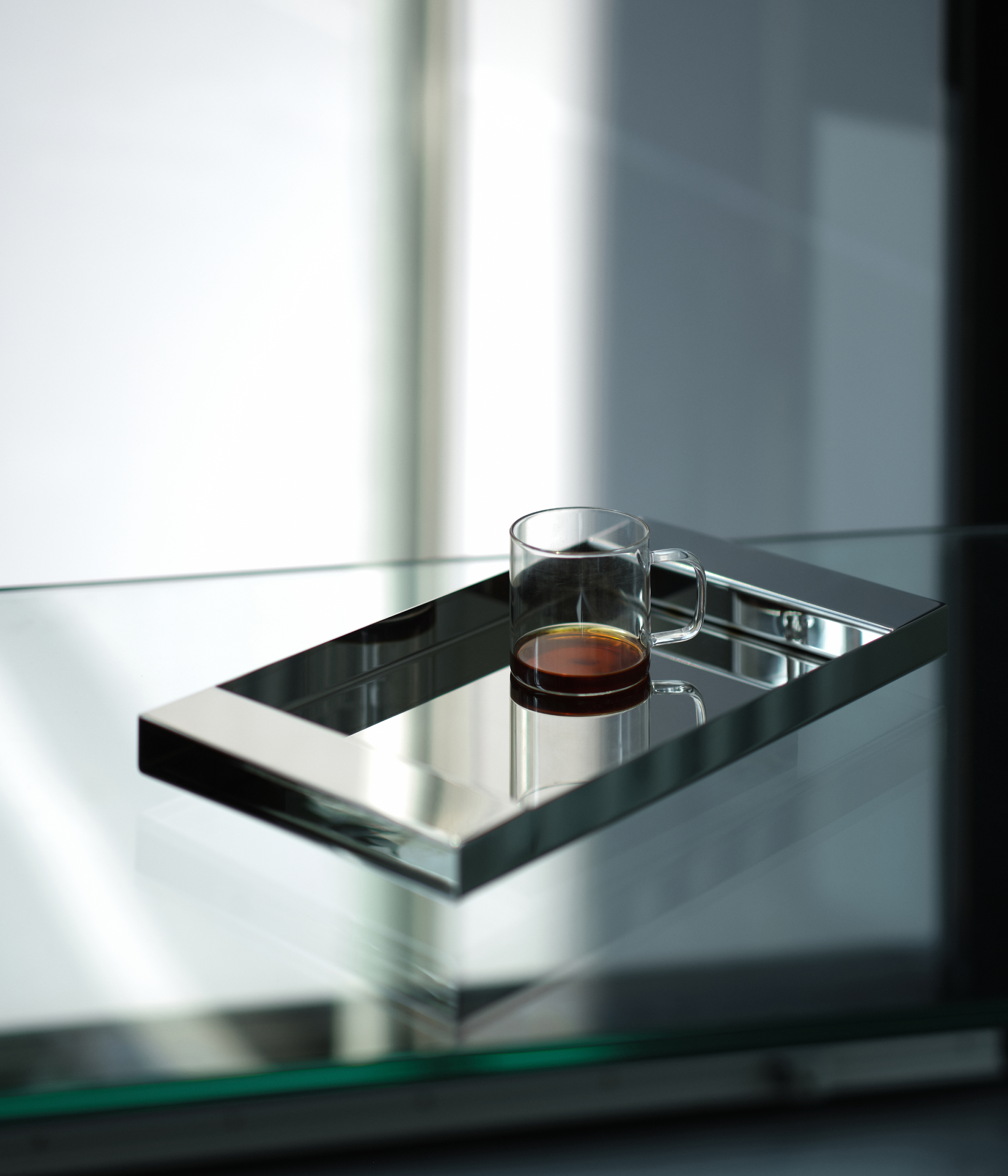 M85 stainless steel tray with mirror polish on a glass table with a coffee mug
