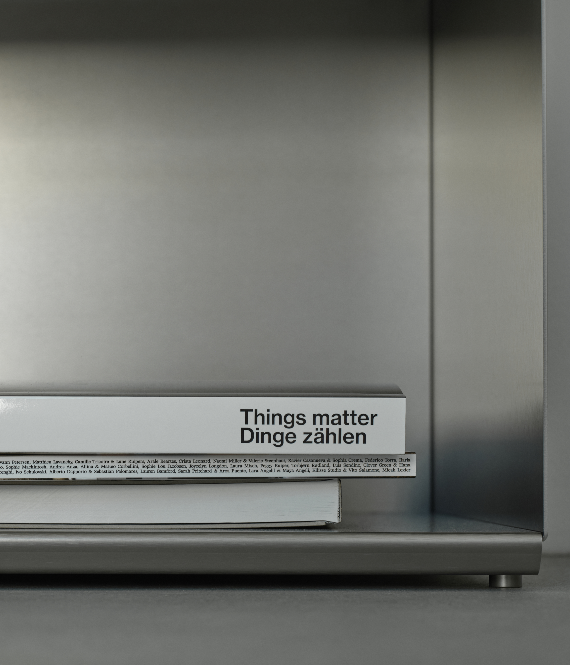 M85 gunmetal aluminum bookshelf with a book titled 'Things matter Dinge zählen' 