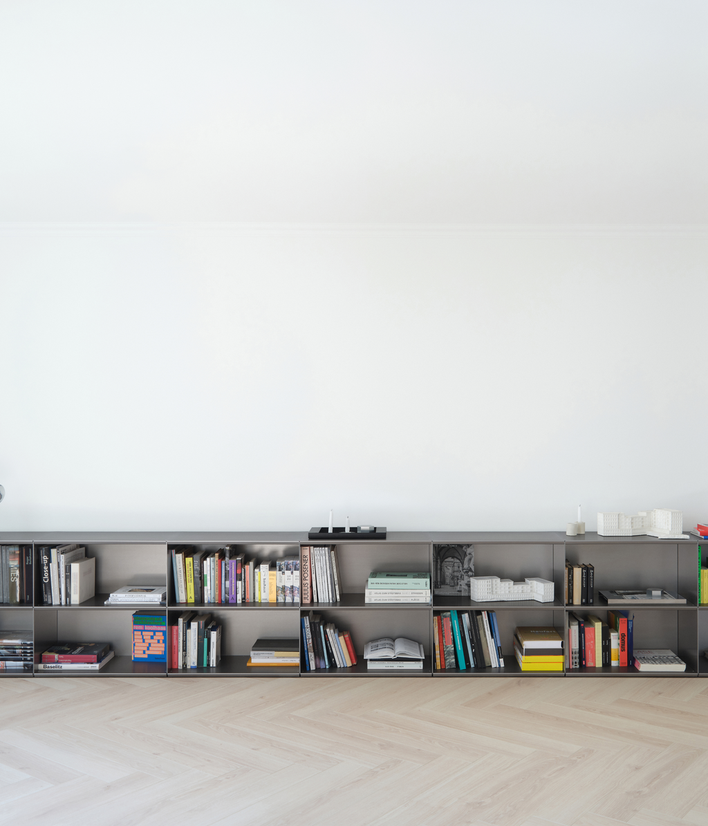 Modern modular M85 aluminum shelf in gunmetal with books and decor against a white wall