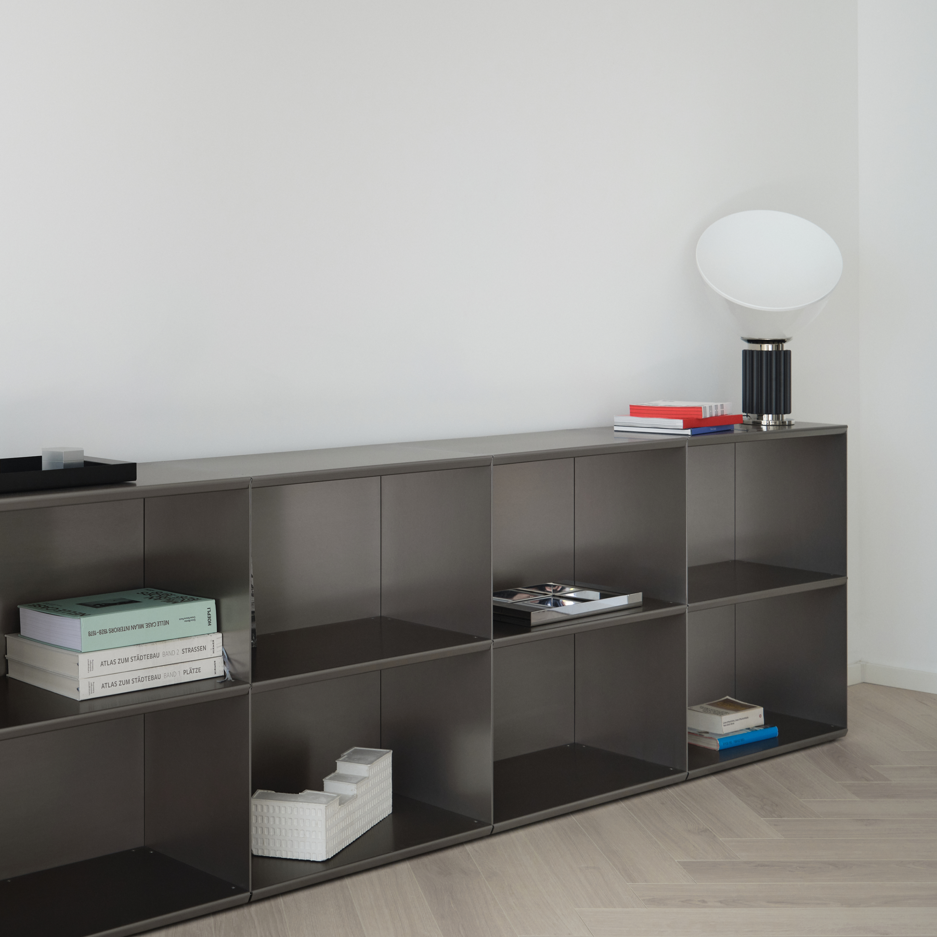 M85 Modern gunmetal grey aluminum modular bookshelf with minimal decor against a white wall