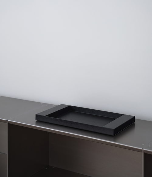 Perspective of black M85 aluminum tray on M85 modular bookshelf with a light gray background