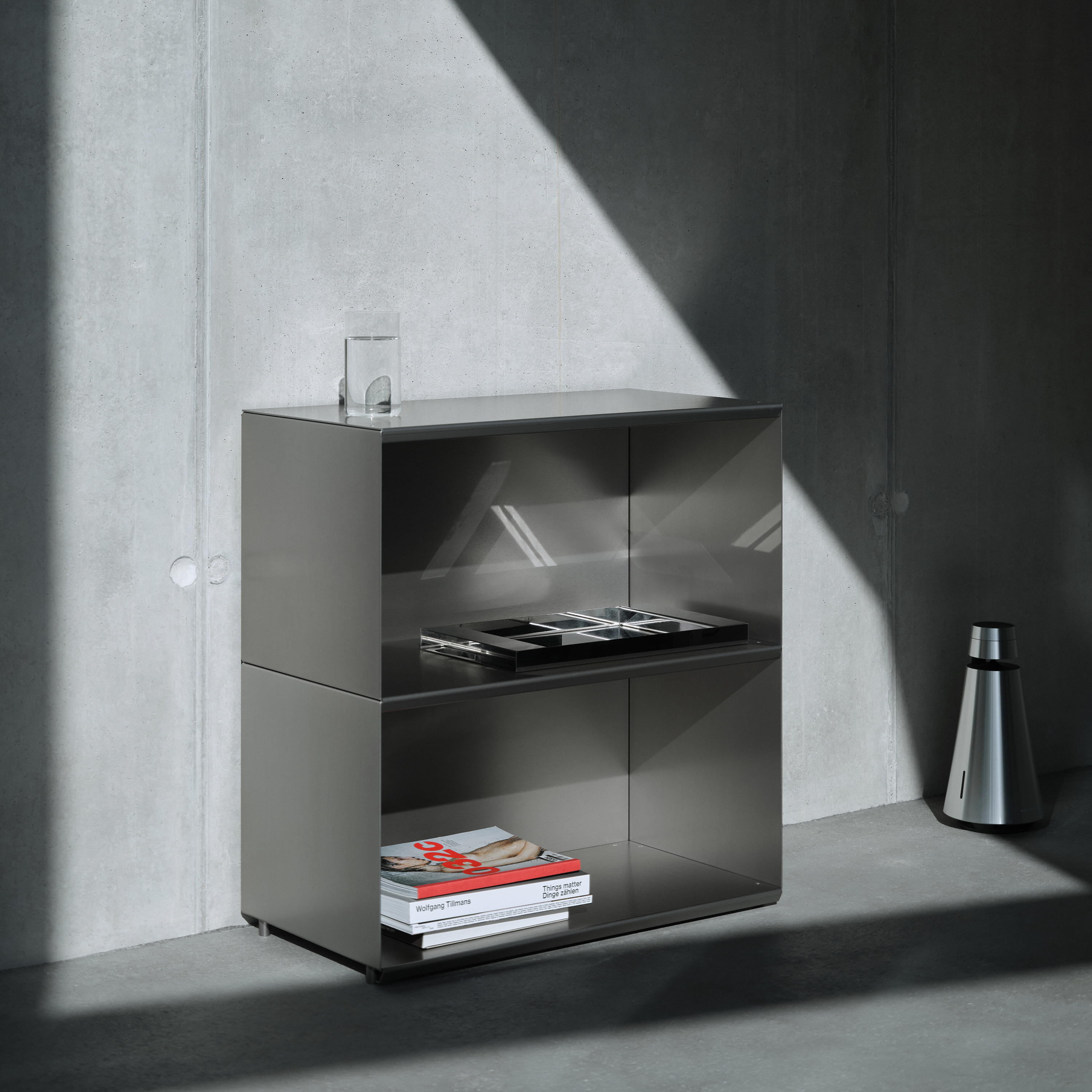 M85 Modern gunmetal grey aluminum modular bookshelf with minimal decor against a concrete wall
