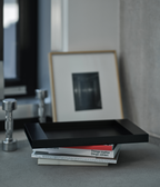 Black M85 tray with books and a framed picture on a gray surface
