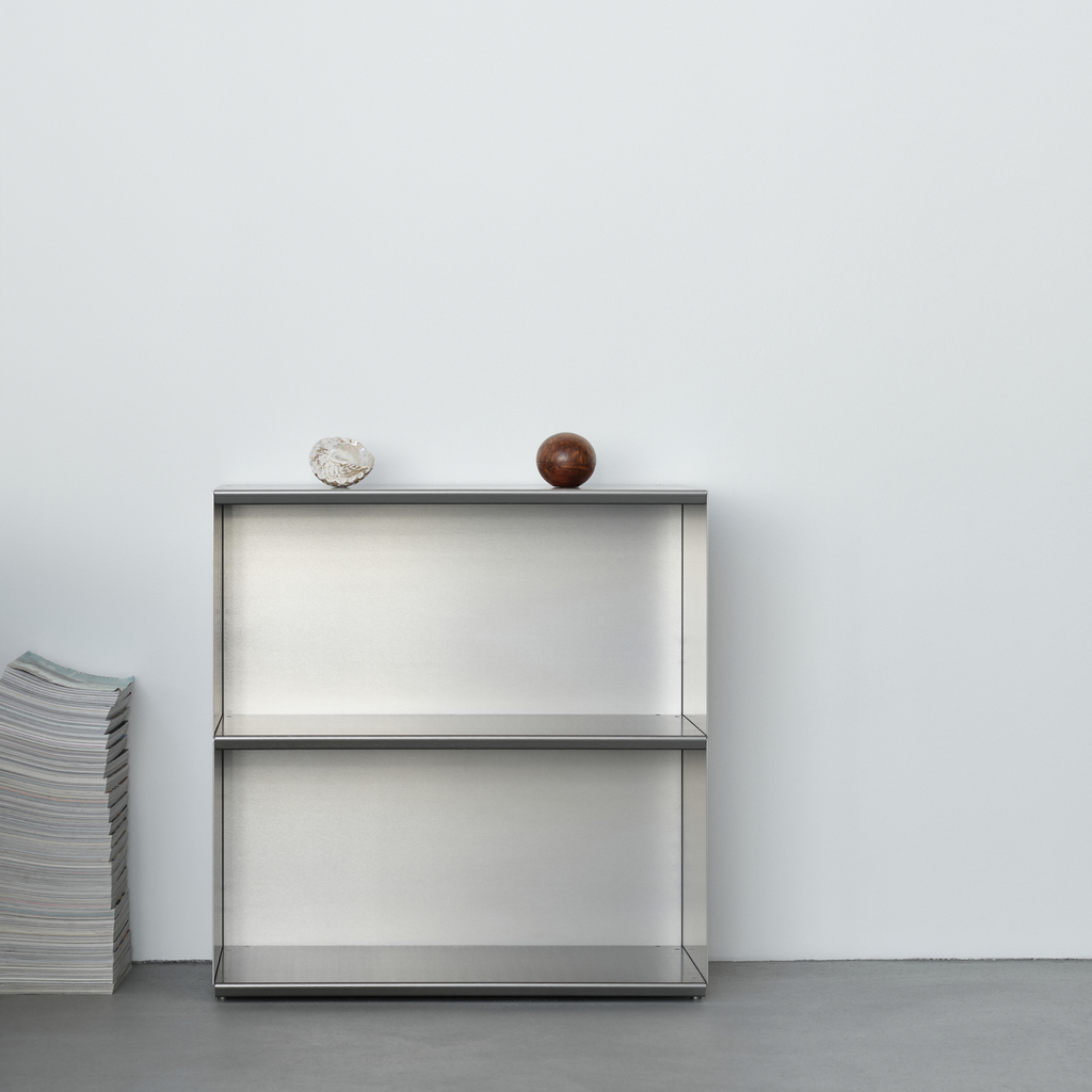 M85 aluminum bookshelf with two decorative items against a white wall