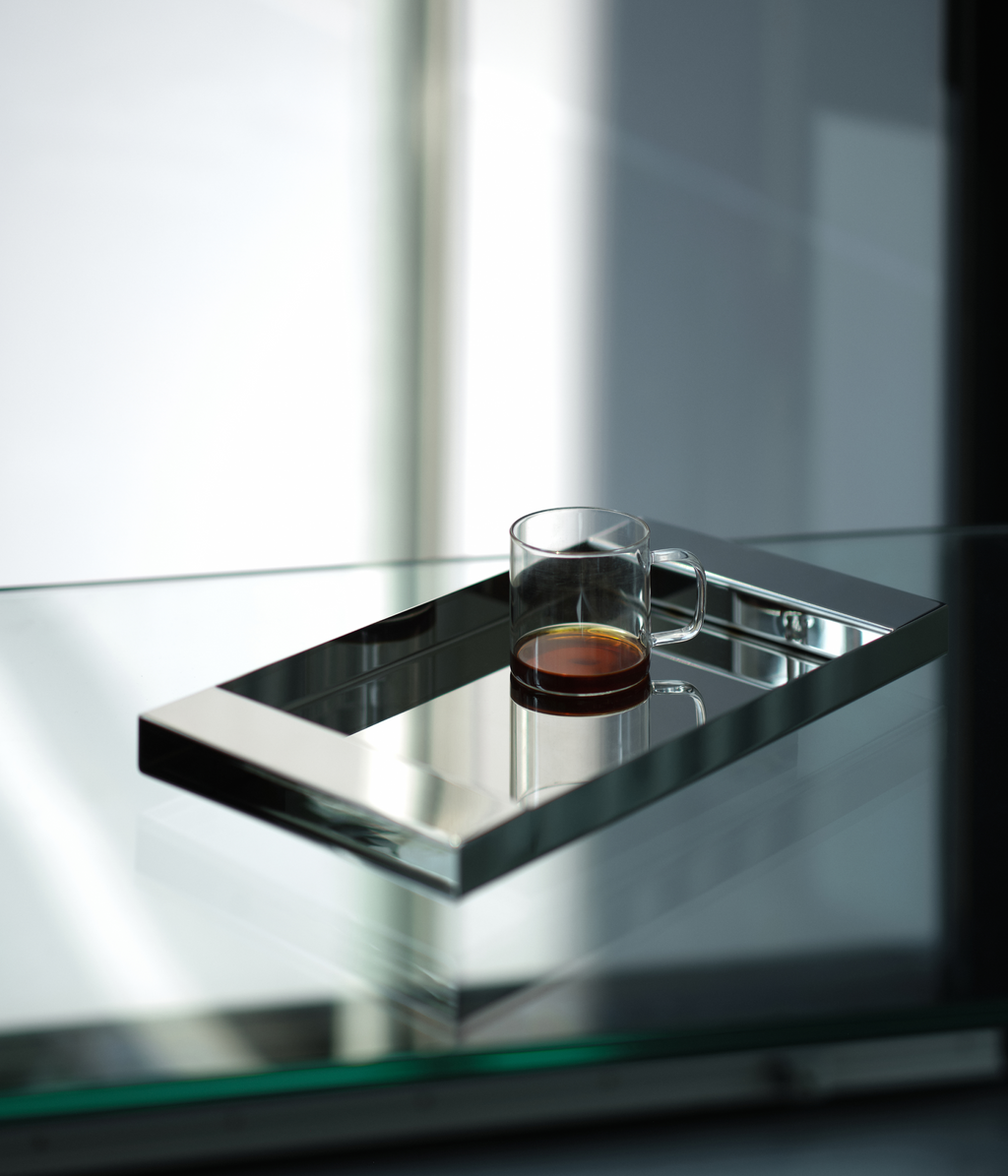 M85 stainless steel tray with mirror polish on a glass table with a coffee mug